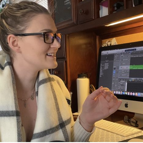 Photo of Samantha in front of her computer, working on production for a song. 
